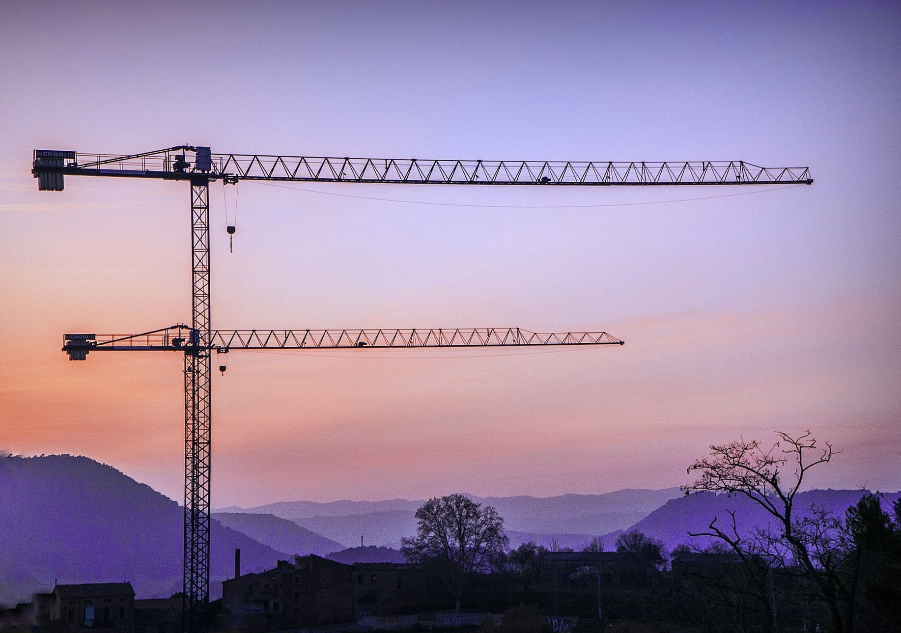 Construction cranes silhouetted against sunset sky representing workplace safety management for ISO 45001 certification